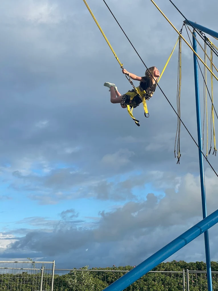 Kind fliegt hoch am gelb-blauen Bungee-Trampolin