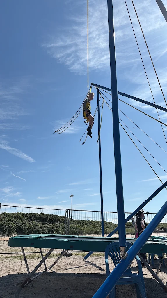 Kind schwebt am Bungee-Trampolin am Strand